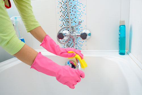 Woman Wearing Gloves Cleans Shower and Bathtub