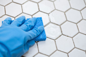 Gloved Hand Scrubbing Tile Grout