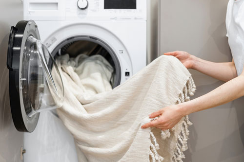 Person Removing Clean Blanket From Dryer
