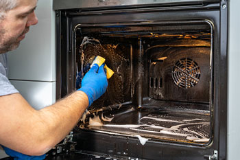 Man Cleans Inside Oven