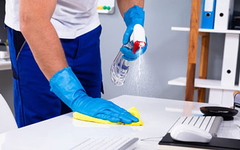 Man Cleaning Desk with Spray and Cloth