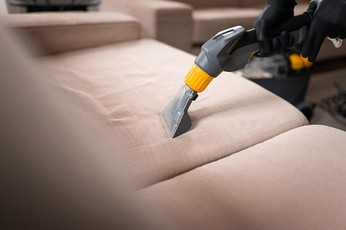 Cleaner Uses Upholstery Vacuum on Couch