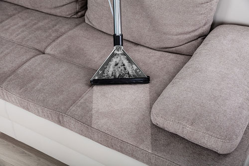 Person Vacuums Gray Couch