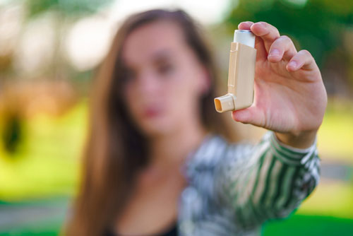 Woman Holds Up Inhaler Used for Treating Asthma